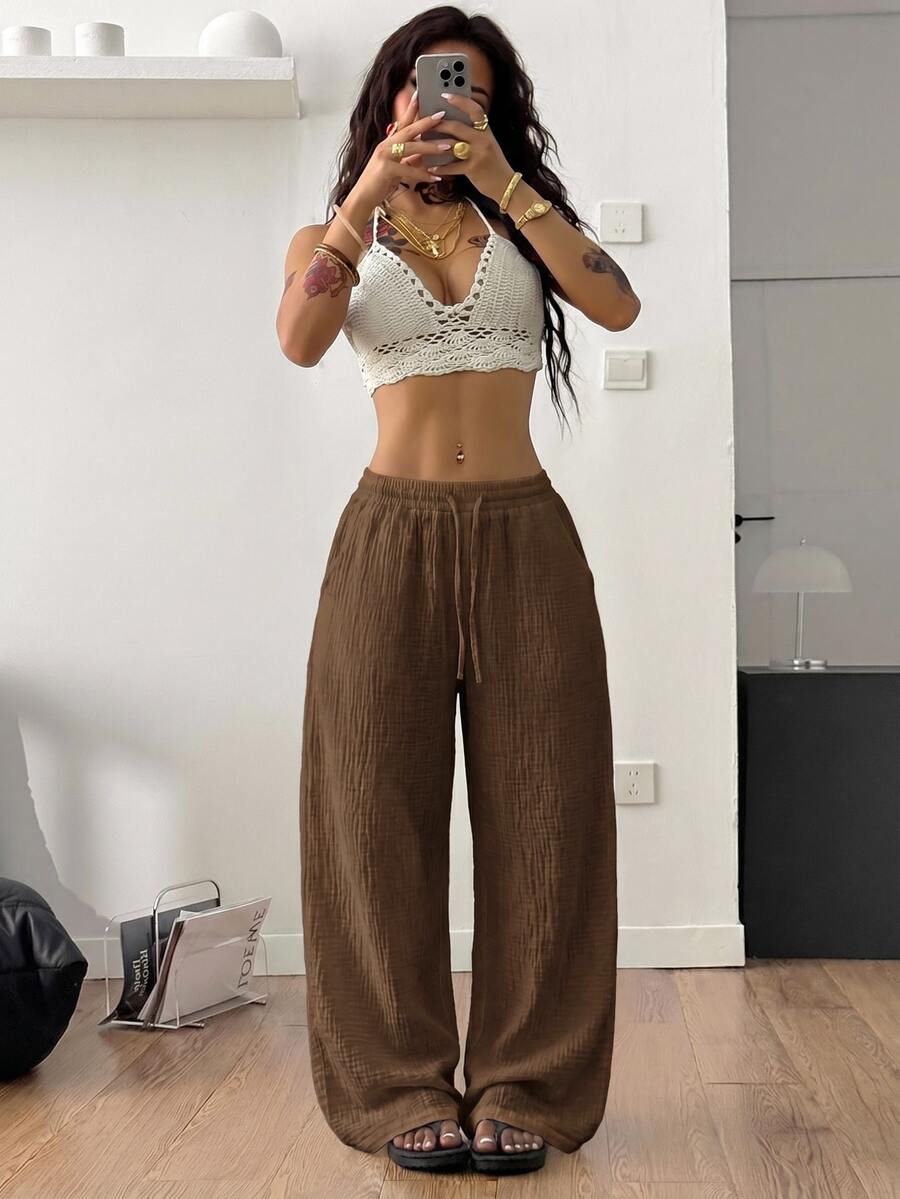 Women's black and white striped wide leg pants featuring an adjustable drawstring waist and side pockets.