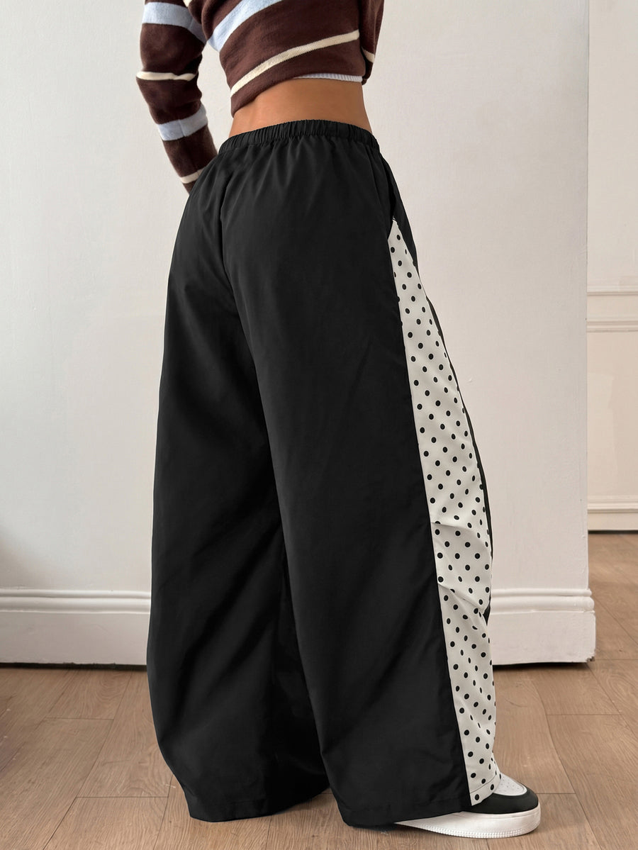 Women's black baggy jogger pants with an adjustable drawstring waist and colorblock polka dot geometric pattern.