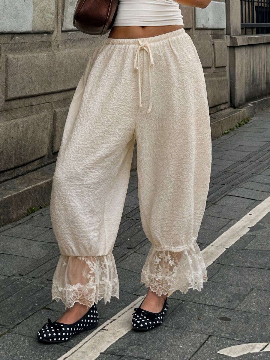 Women's loose-fitting lantern bloomer pants in capri length featuring delicate contrast lace trim and a drawstring waist.