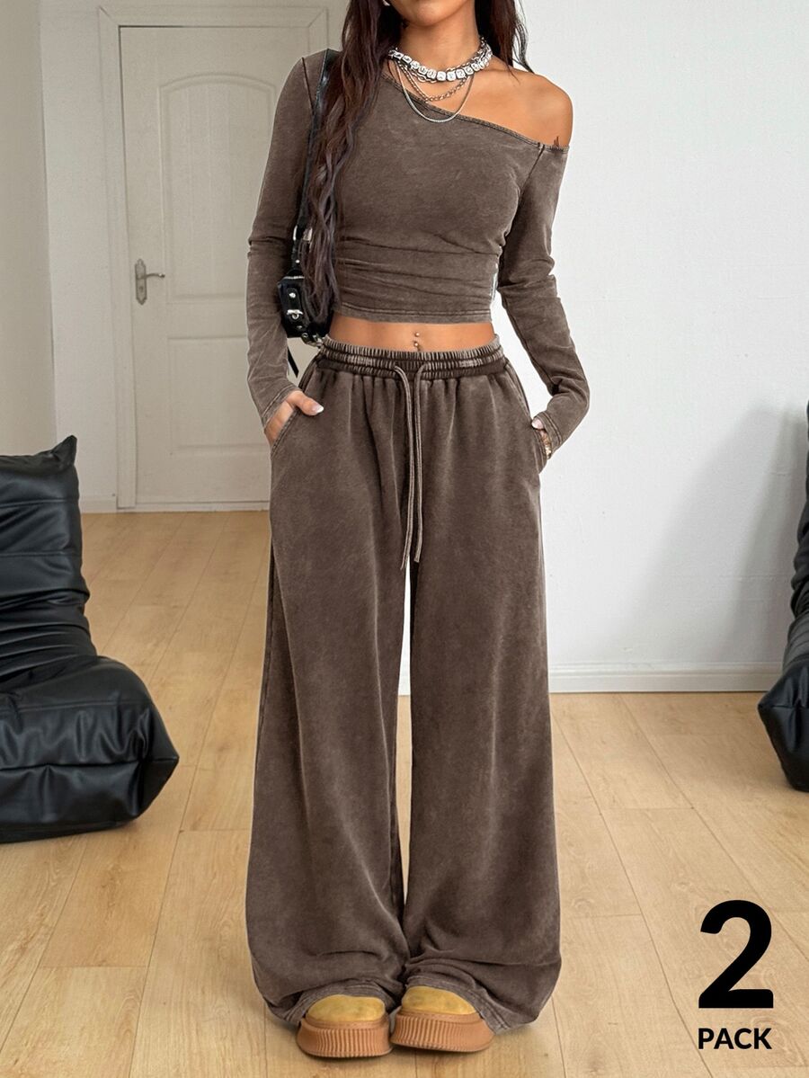 Women's two-piece knit lounge set featuring a black long sleeve asymmetrical crop top and matching high-waisted wide leg sweatpants.