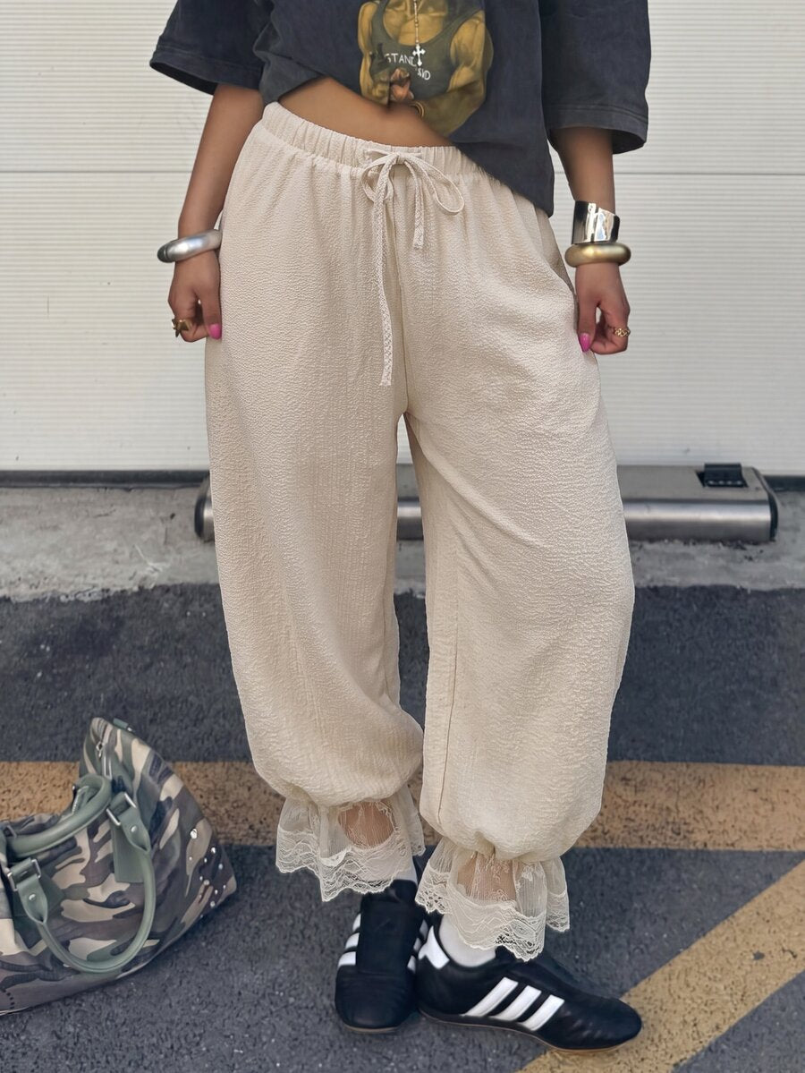 Women's loose-fitting lantern bloomer pants in capri length featuring delicate contrast lace trim and a drawstring waist.