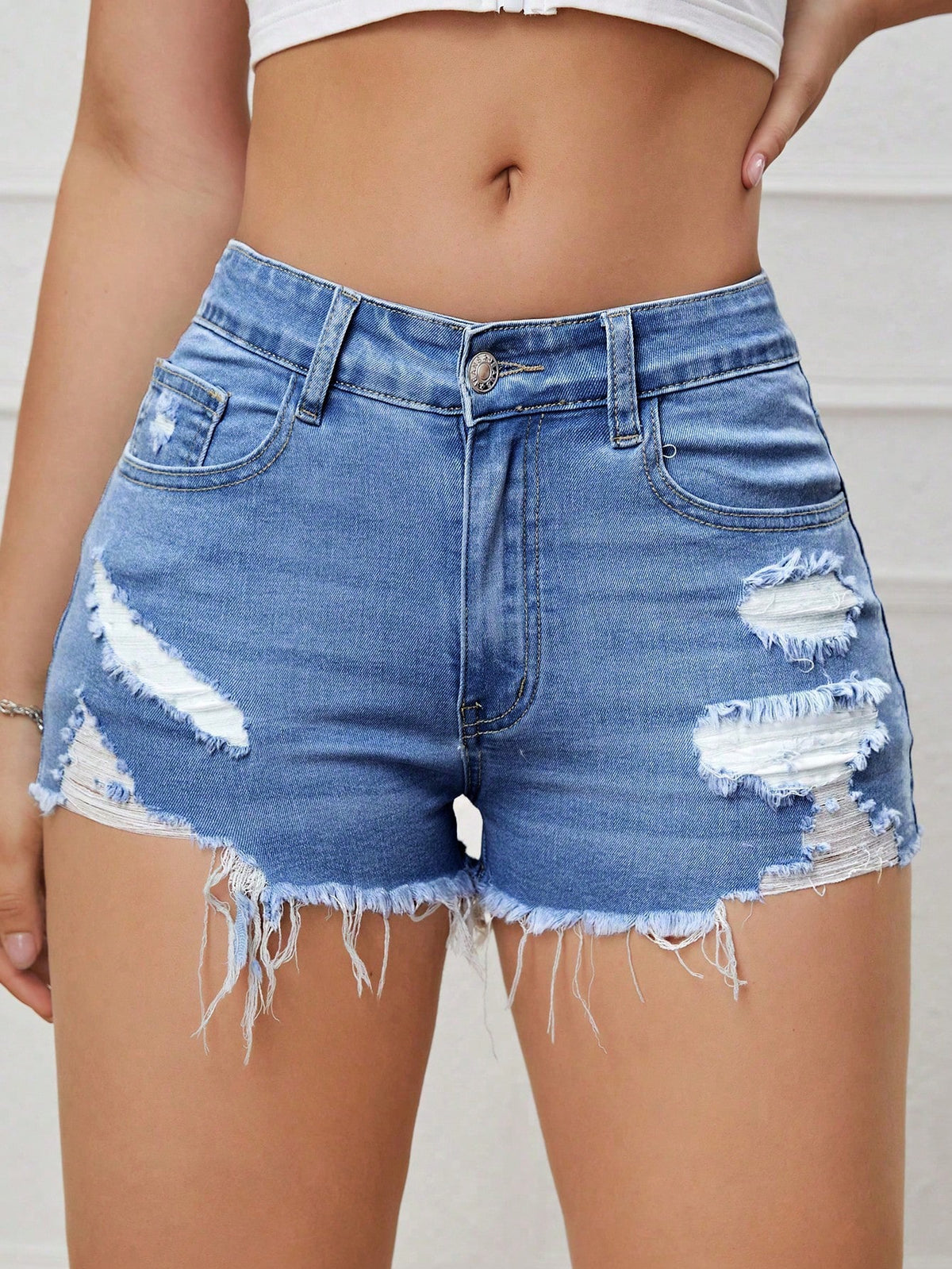 Women's solid color shorts with zipper fly, button closure, pockets, ripped details, and raw hem in a casual straight-leg short length