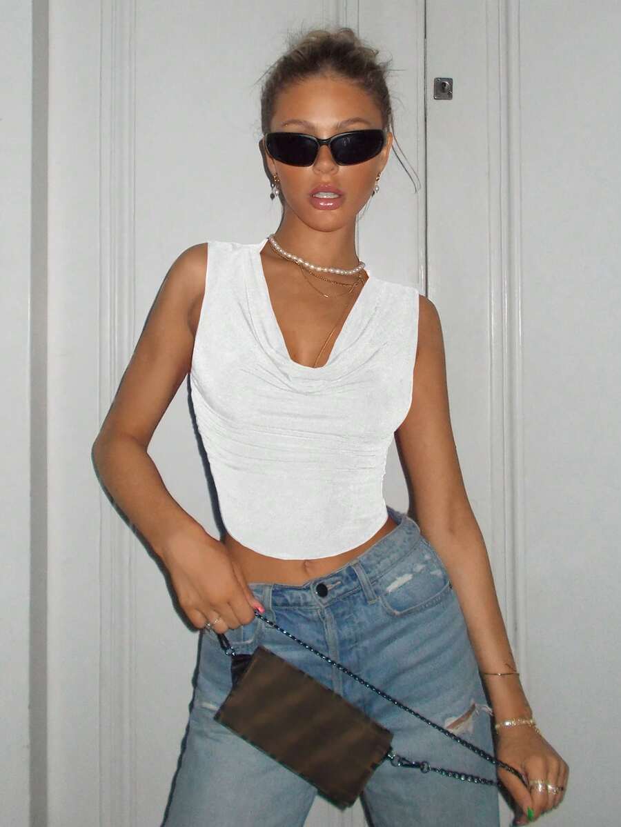 White crop tank top with draped cowl neck, backless design, slim fit, and asymmetrical curved hem