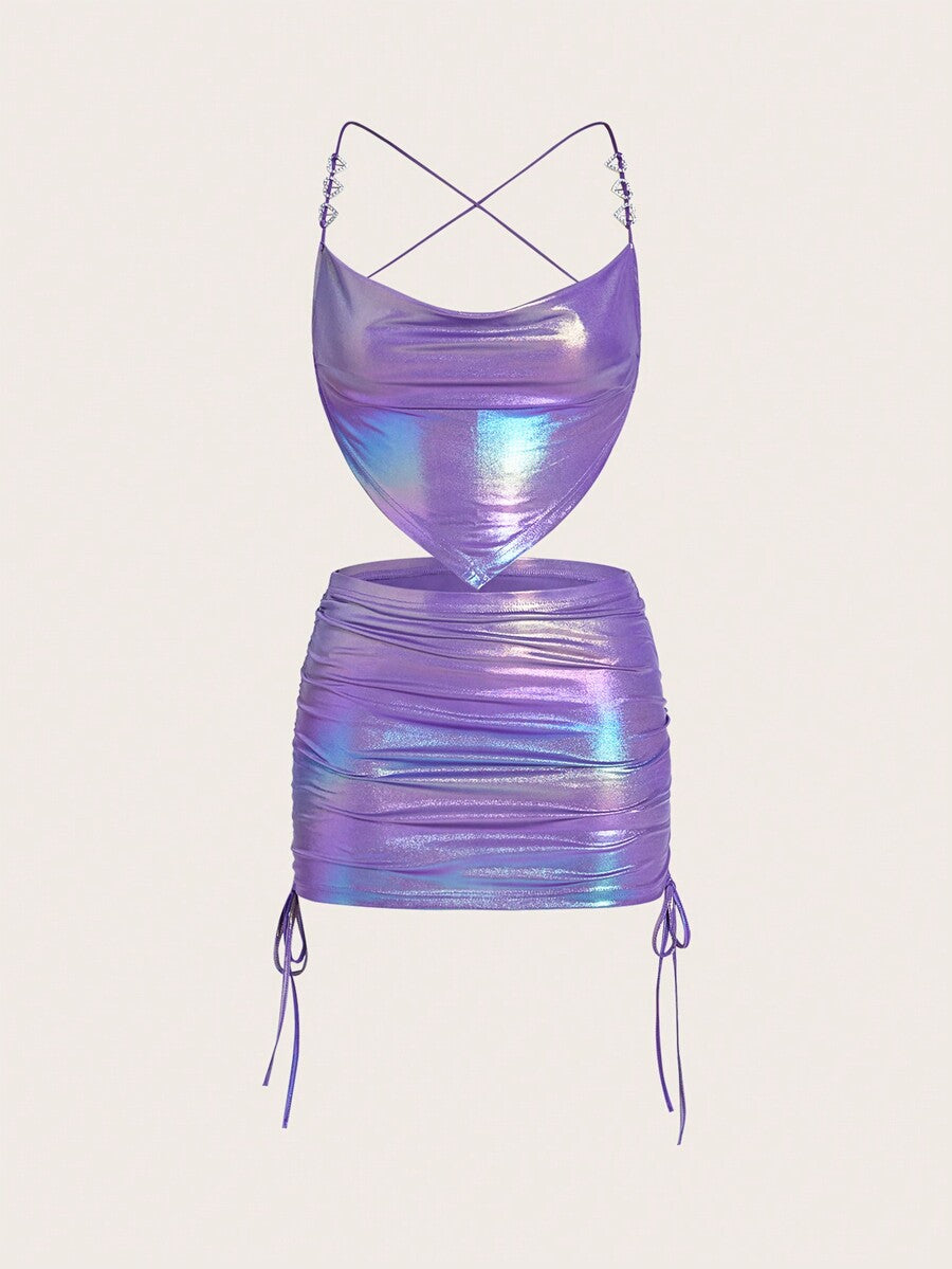 Holographic metallic two-piece set with a spaghetti strap hanky hem crop cami top and drawstring side skirt, featuring ruched details and rhinestone accents.