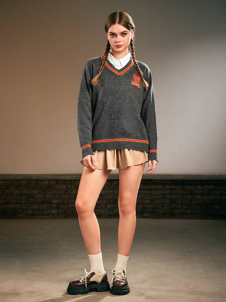 Women's grey V-neck knit pullover sweater featuring drop shoulder long sleeves, striped contrast trim along the neckline, and chest embroidery.
