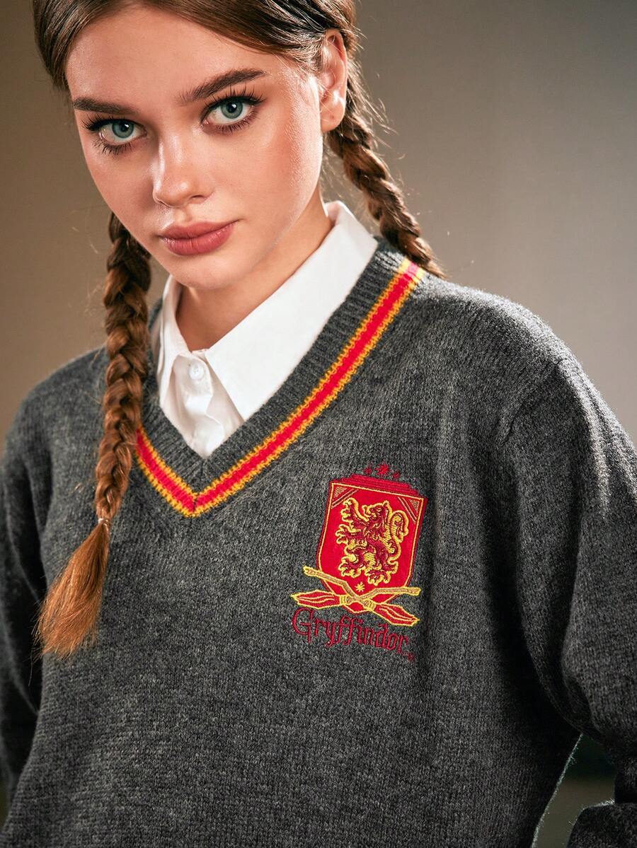 Women's grey V-neck knit pullover sweater featuring drop shoulder long sleeves, striped contrast trim along the neckline, and chest embroidery.