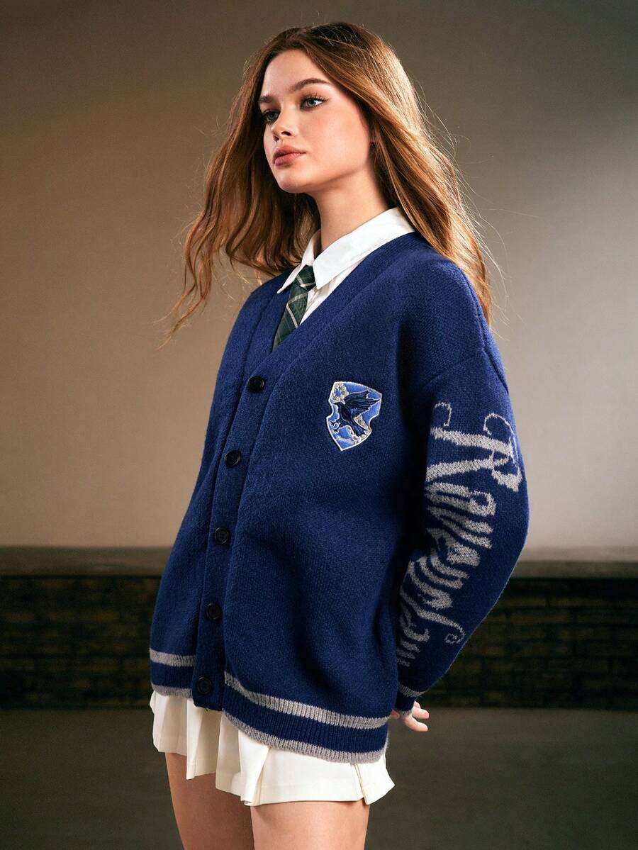 Women's blue loose knit cardigan sweater featuring a V-neckline, button-down front, letter embroidered badge, and dropped shoulders.