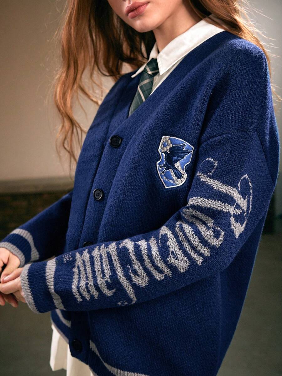 Women's blue loose knit cardigan sweater featuring a V-neckline, button-down front, letter embroidered badge, and dropped shoulders.