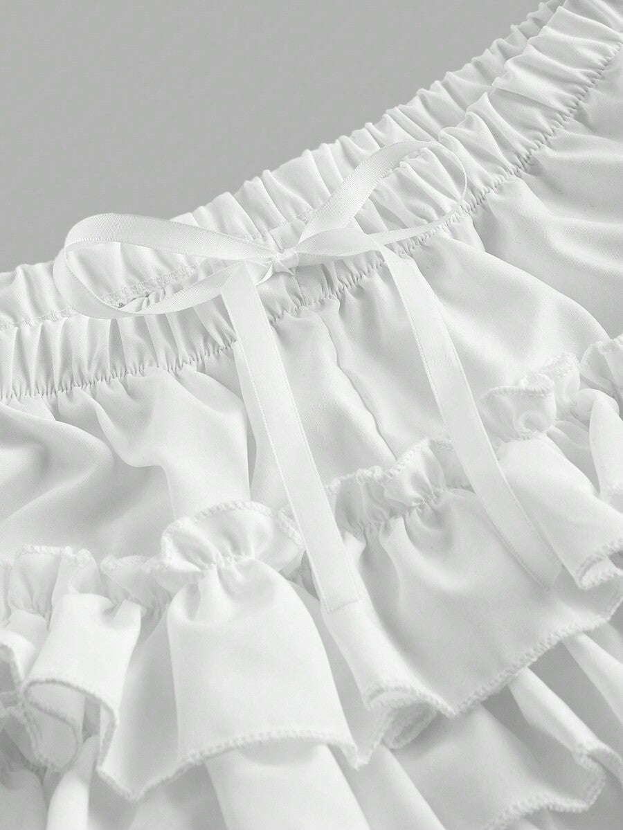 Women's tiered ruffle skort shorts featuring an elastic mid waist with front tie knot detail in woven fabric.