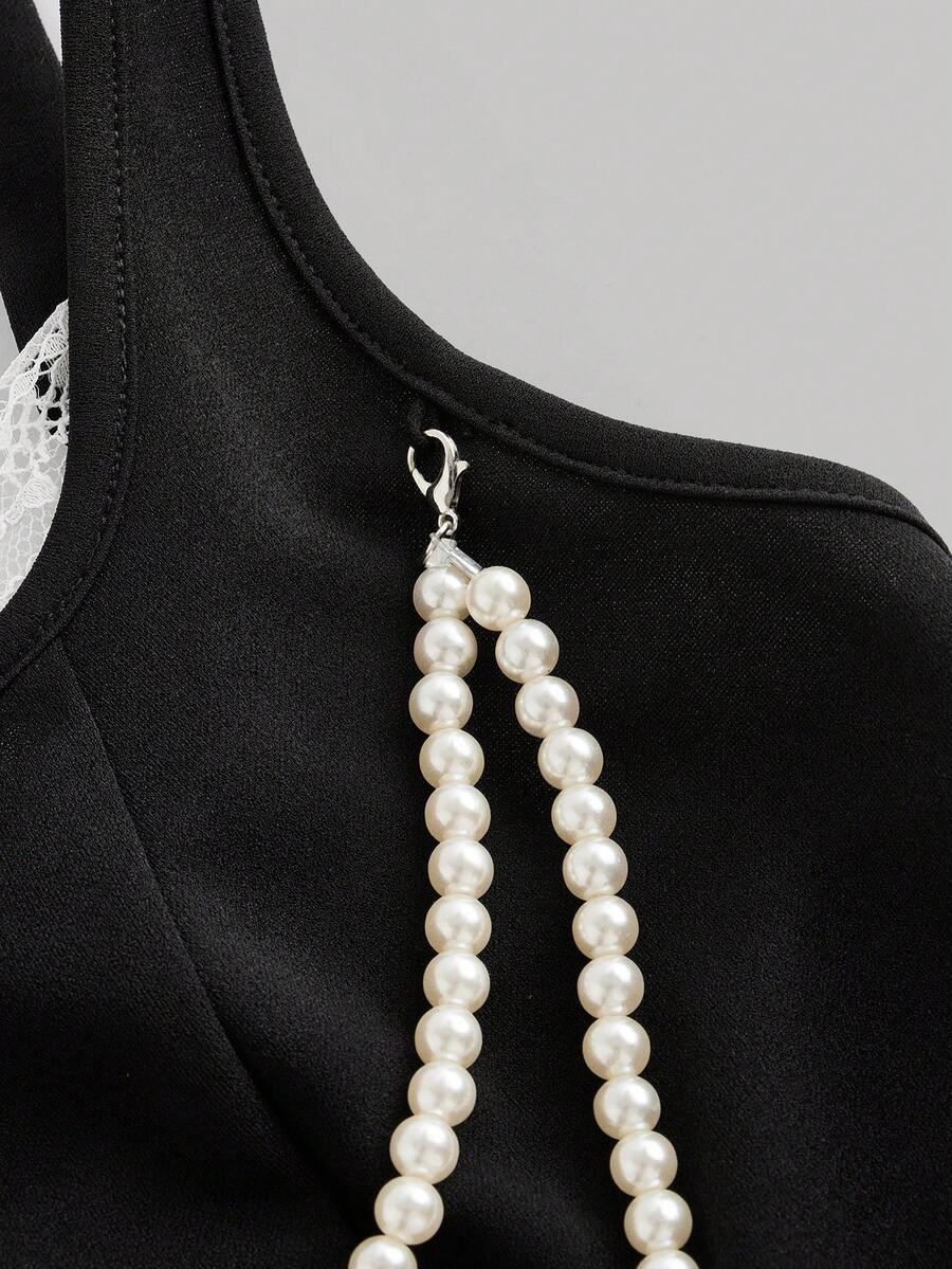 women's black wide-strap tank top featuring a lace collar, detachable bow chain decor with pearl details, and an asymmetrical hem.