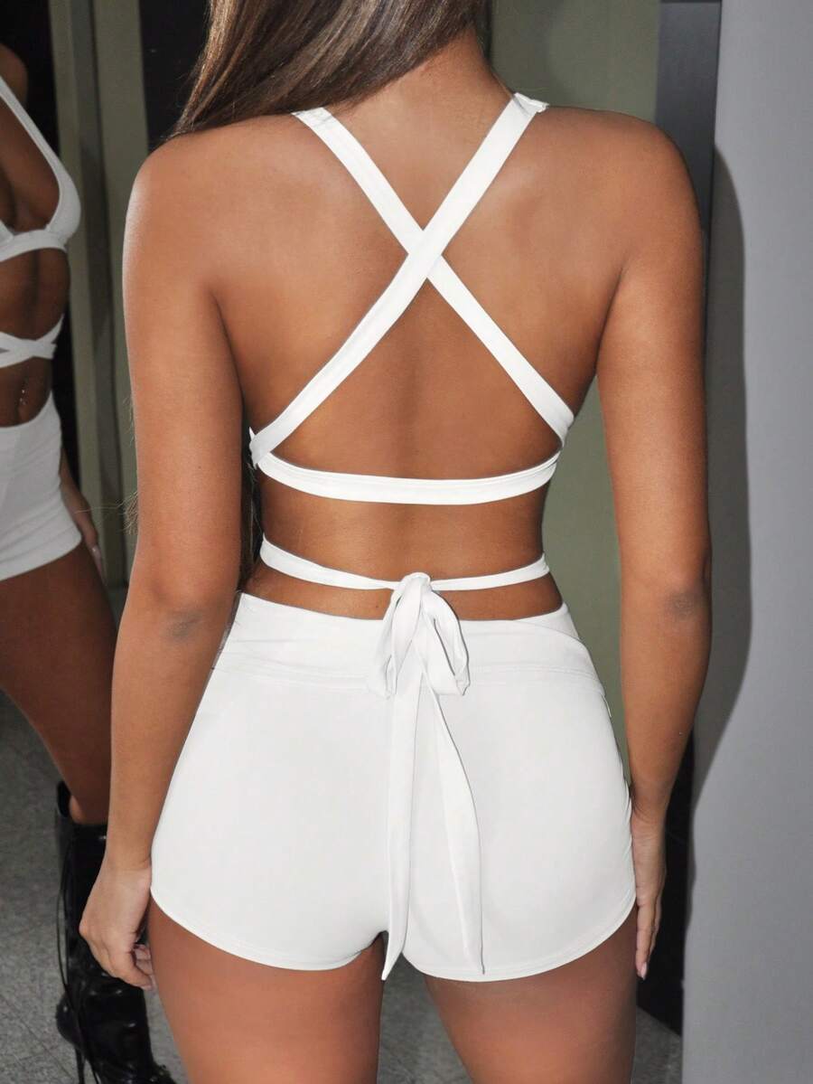 Y2K two-piece outfit with a backless halter crop top, deep V neckline, crisscross lace-up detail, and low-waist slim fit mini shorts.