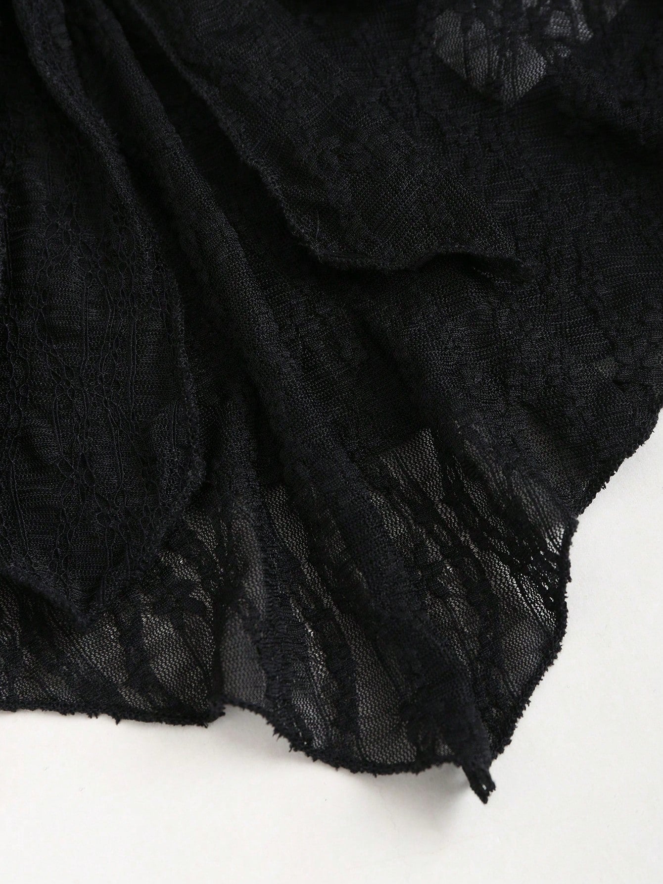 Women's black lace halter crop top with contrast bow front, backless styling, semi-sheer finish, and asymmetrical hem