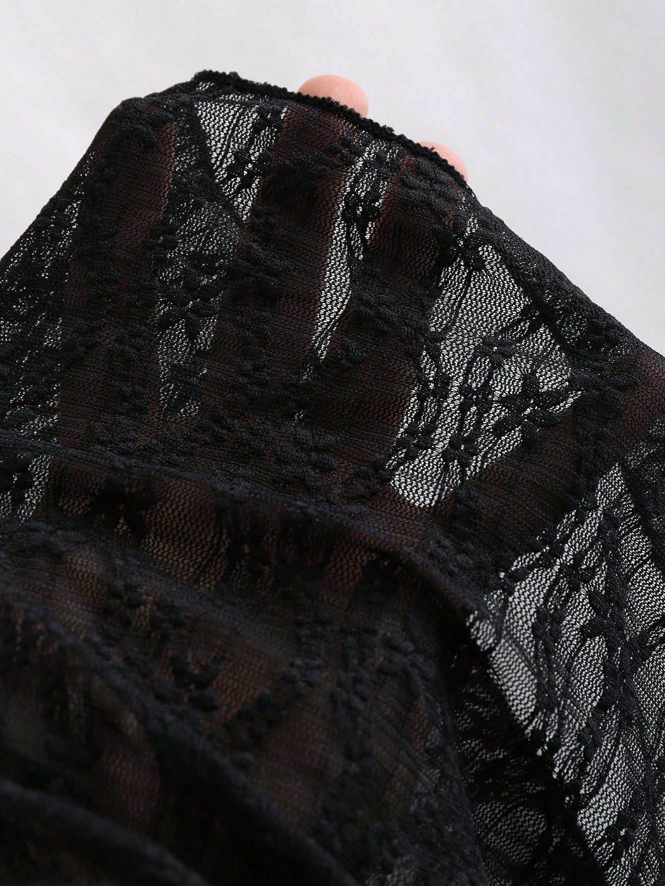 Women's black lace halter crop top with contrast bow front, backless styling, semi-sheer finish, and asymmetrical hem