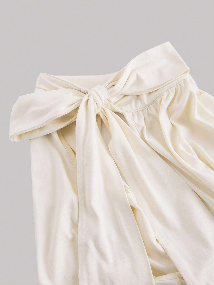 Women's sleeveless high-neck halter crop top in apricot with ruched knot front detailing.