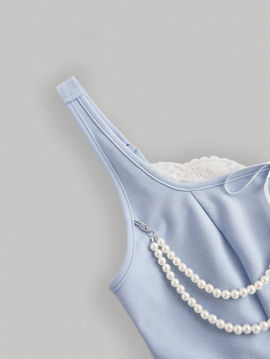women's black wide-strap tank top featuring a lace collar, detachable bow chain decor with pearl details, and an asymmetrical hem.