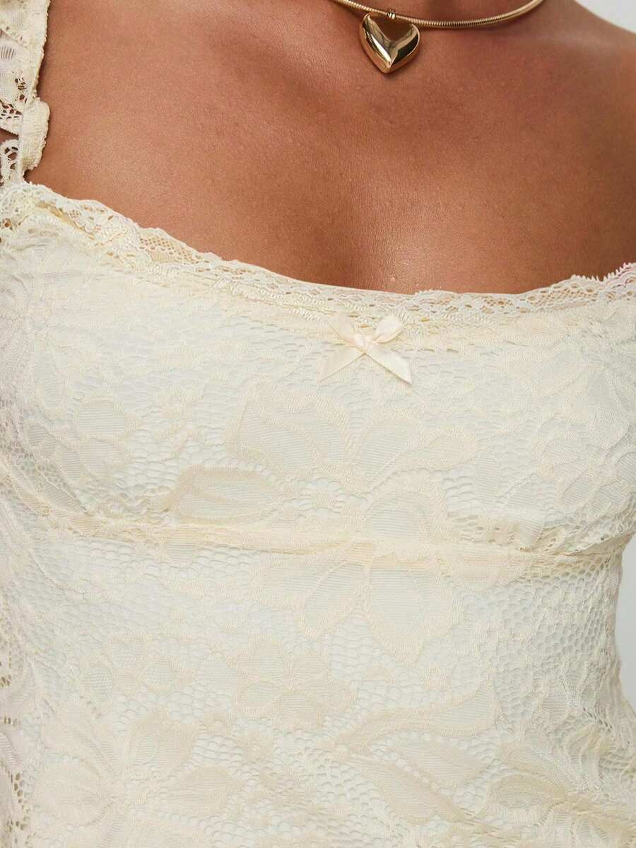 Sleeveless cami tank top featuring contrast lace patchwork design, ruffle spaghetti straps, and bow decor.