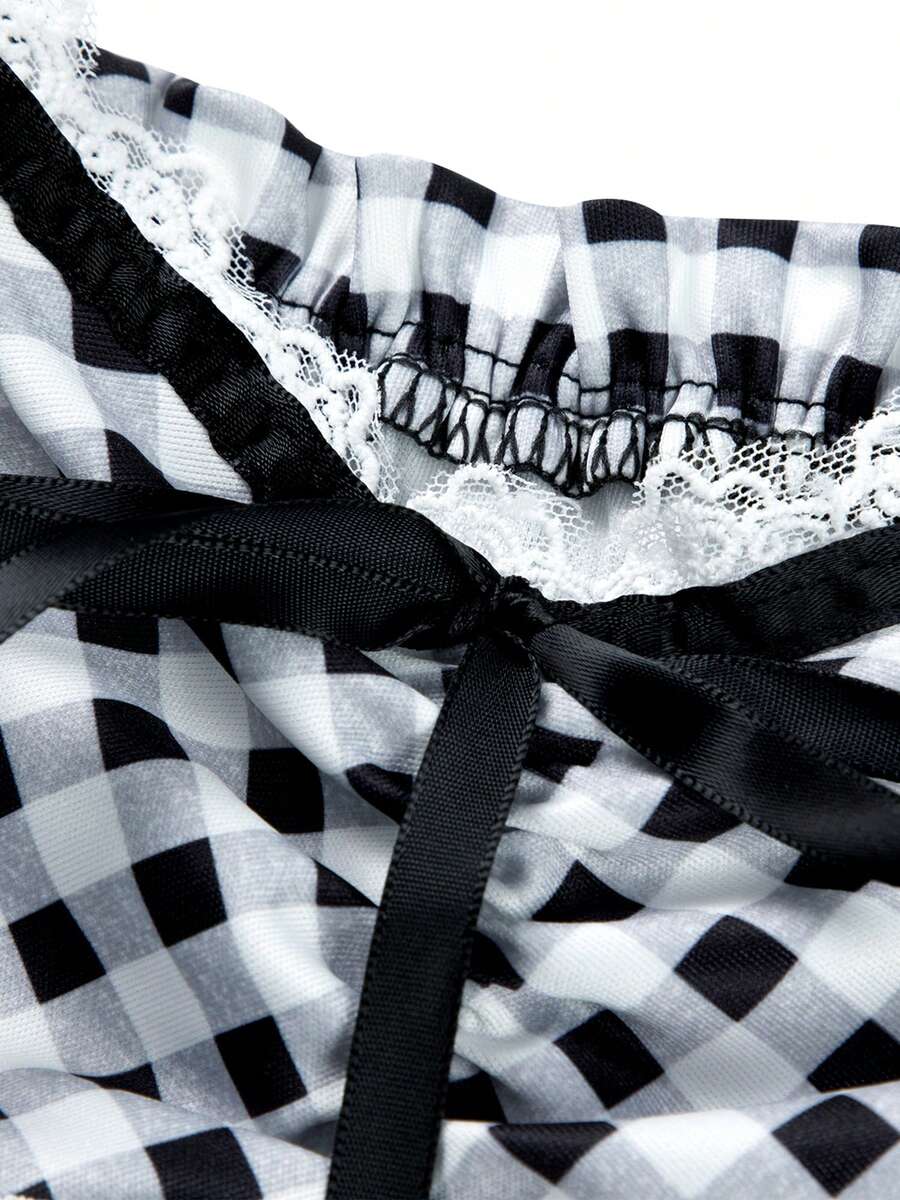 Women's black and white plaid short sleeve blouse featuring a tie-front front bow, contrast lace frill trim, raglan sleeves, and sweetheart neckline.