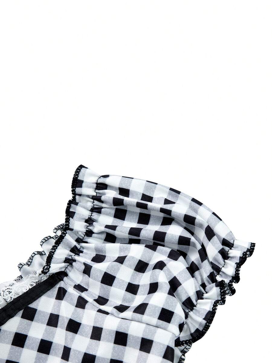 Women's black and white plaid short sleeve blouse featuring a tie-front front bow, contrast lace frill trim, raglan sleeves, and sweetheart neckline.