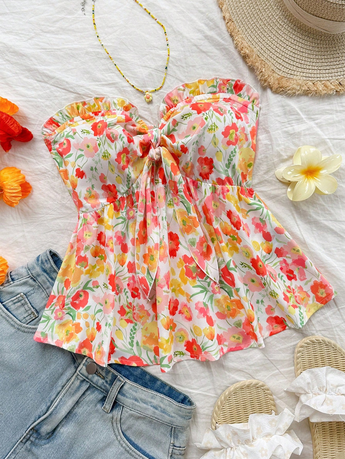 Women's woven strapless bandeau top in multicolor floral print featuring ruffle trim, frill details, and a flared hem.