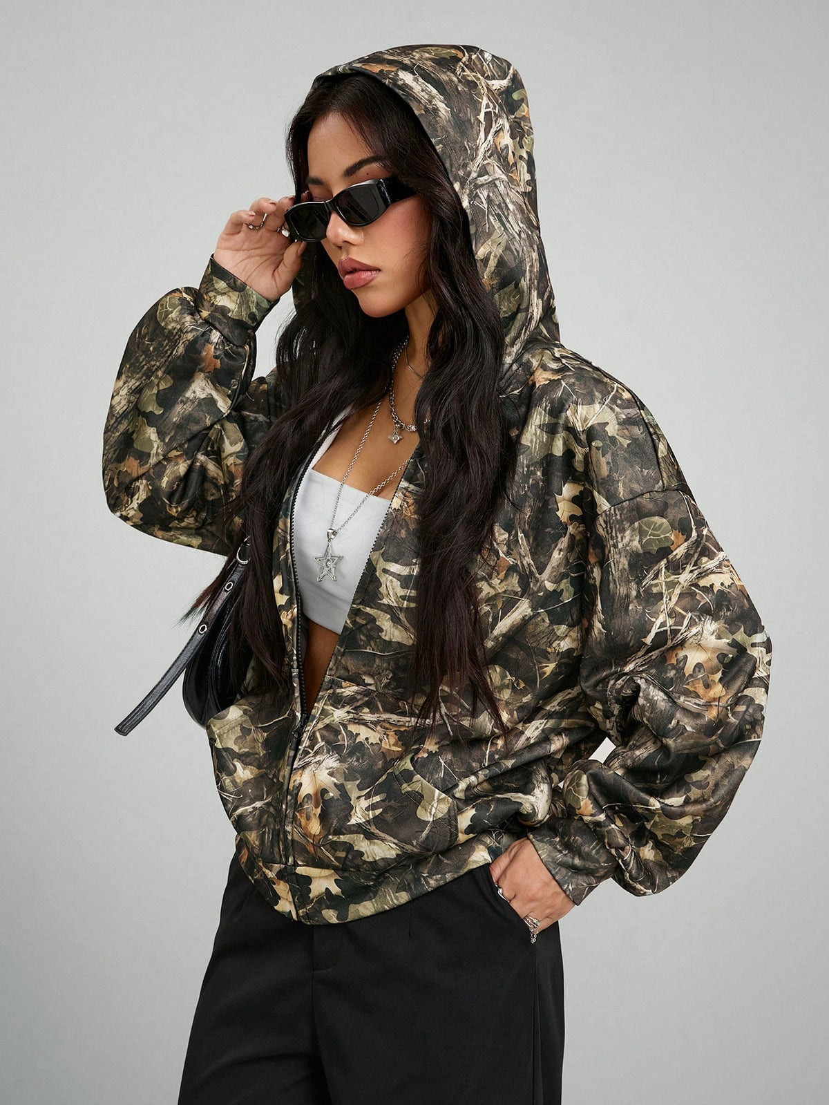 Women's army green camo zip up hoodie with drop shoulder sleeves, front pockets, and drawstring hood