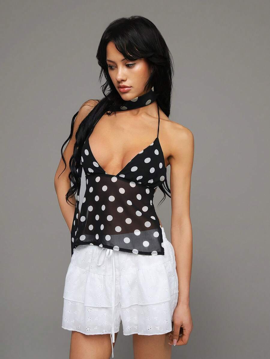 Women's black polka dot halter crop tank top with button front detail and asymmetrical hem.