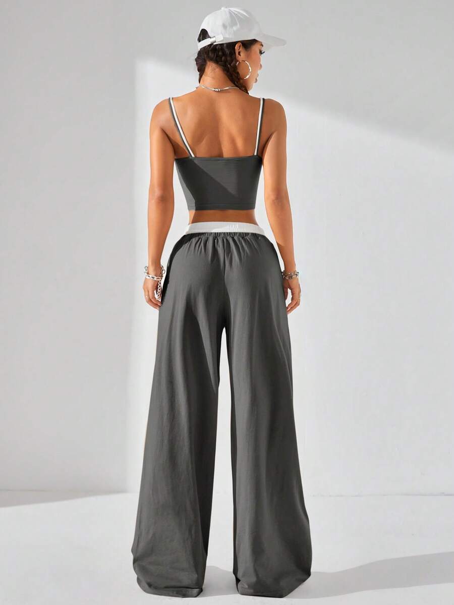 Dark grey women's two-piece outfit featuring a spaghetti strap cami crop top with contrast binding and matching wide-leg drawstring knit lounge pants.