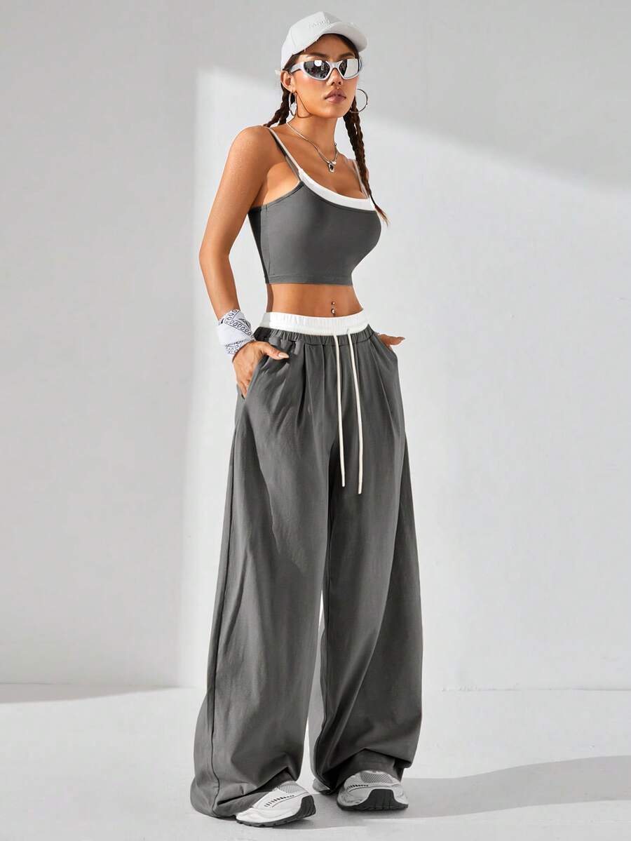 Dark grey women's two-piece outfit featuring a spaghetti strap cami crop top with contrast binding and matching wide-leg drawstring knit lounge pants.