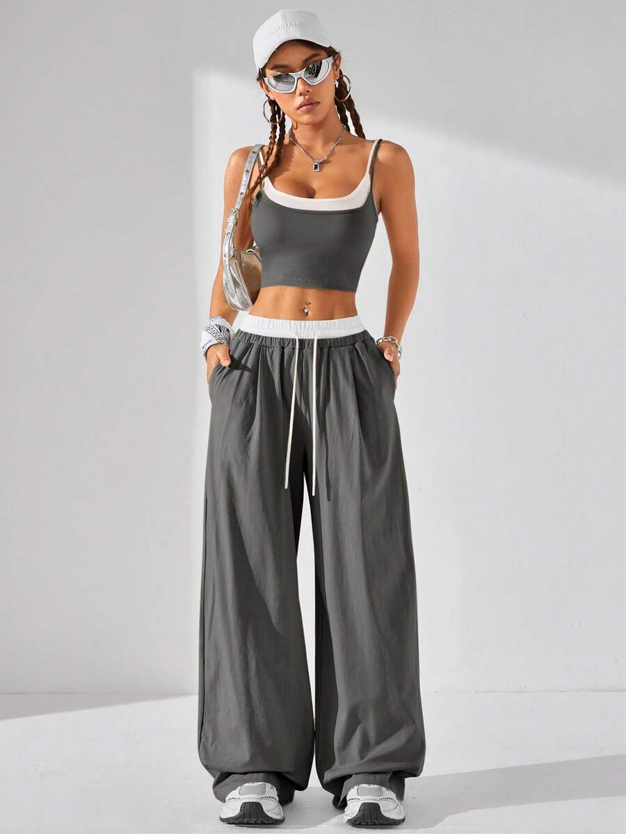 Dark grey women's two-piece outfit featuring a spaghetti strap cami crop top with contrast binding and matching wide-leg drawstring knit lounge pants.