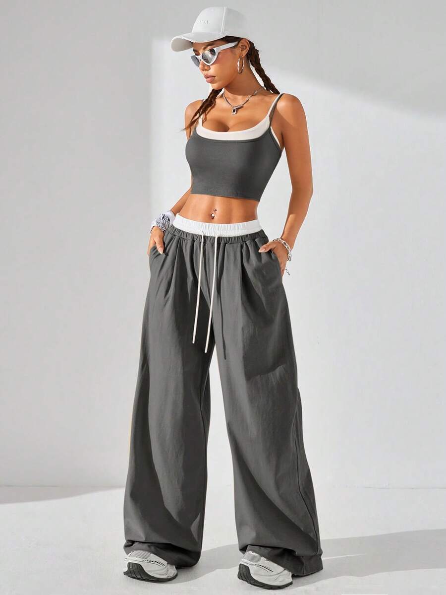 Dark grey women's two-piece outfit featuring a spaghetti strap cami crop top with contrast binding and matching wide-leg drawstring knit lounge pants.