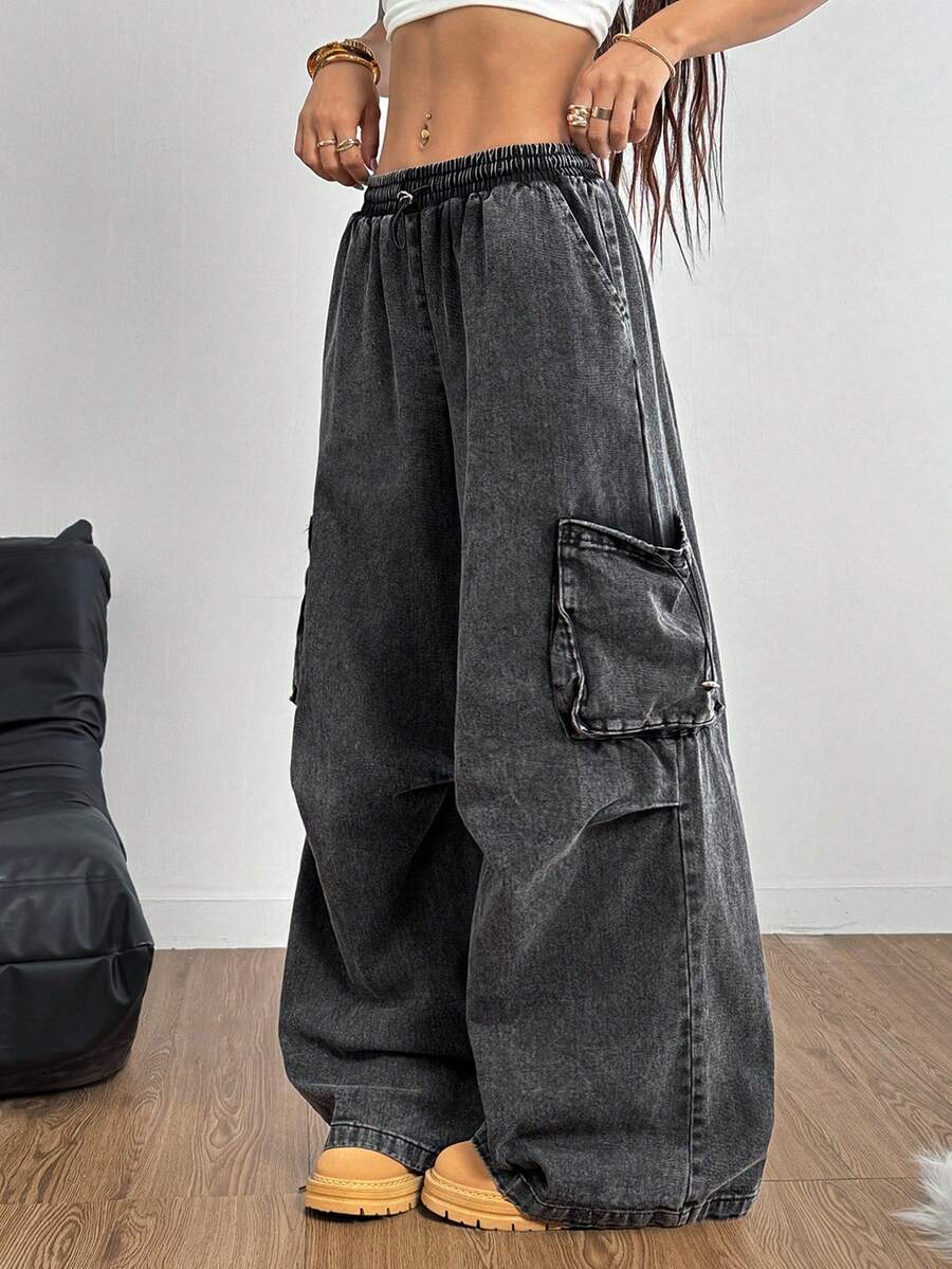 Women's black baggy cargo pants featuring a wide-leg cut, low-rise drawstring waist, and 100% cotton woven fabric.