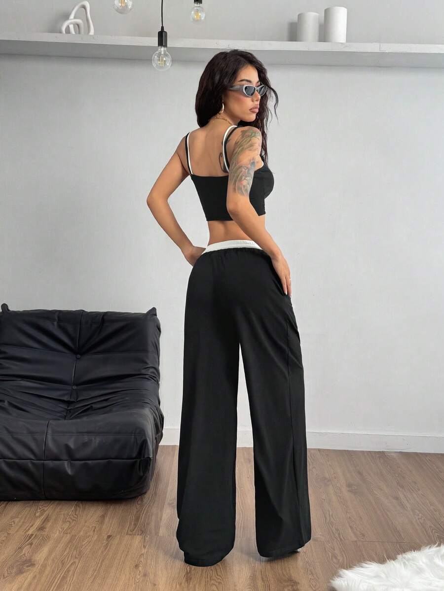 Women's black and white two-piece set featuring a cropped spaghetti strap camisole tank top with contrast binding and matching long drawstring sweatpants with pockets.