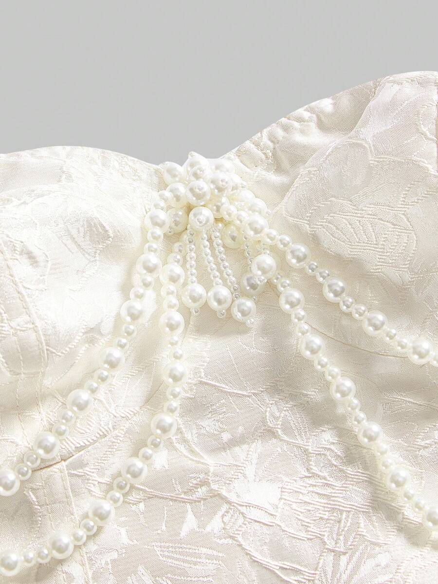Women's apricot strapless vintage palace style blouse featuring an asymmetrical ruffle hem, backless design, and pearl brooch detail.
