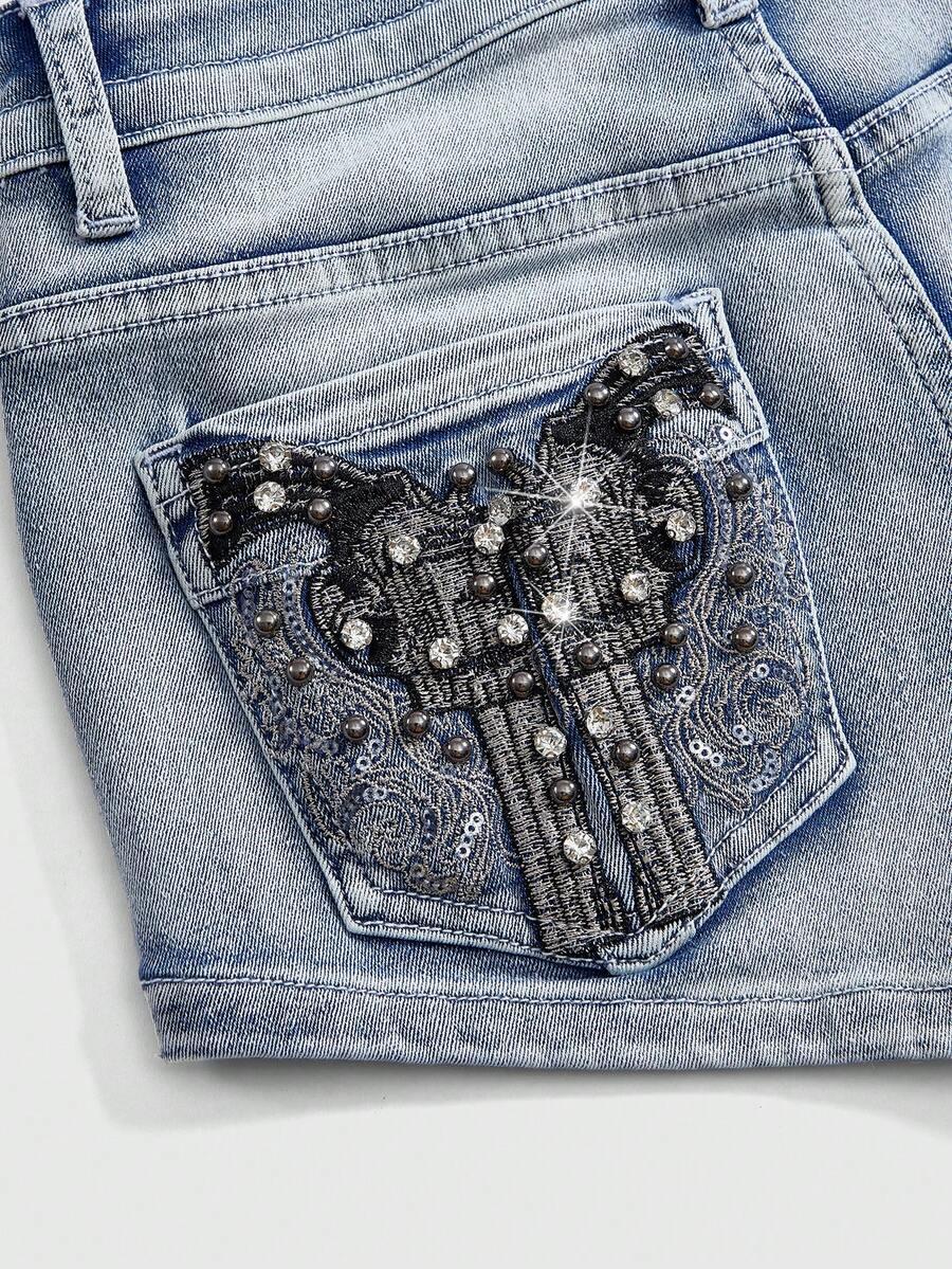 Women's ultra low waist skort with mini shorts length, zipper fly, pockets, pistol embroidery, and rhinestone details