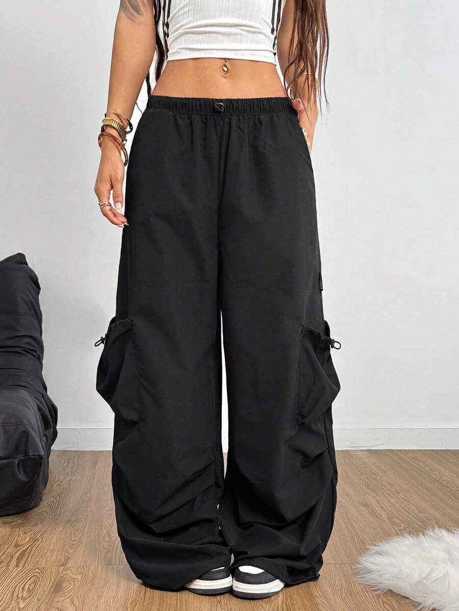 Women's loose black wide leg cargo pants featuring a low waist and drawstring waistband.