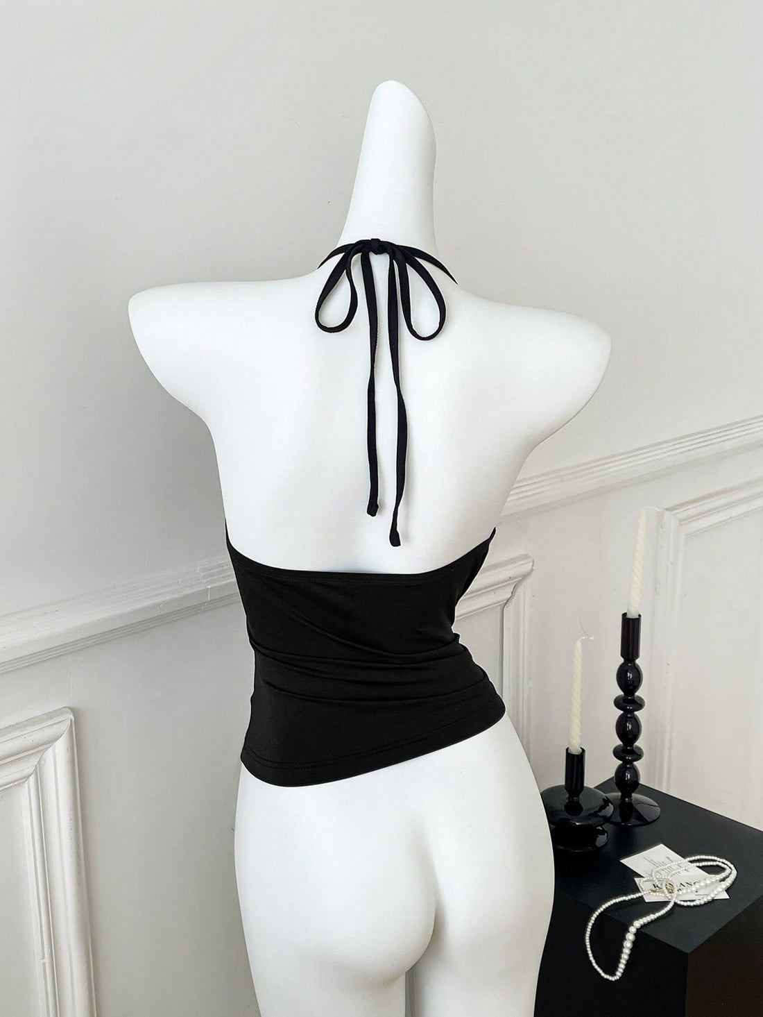 Women's black halter crop tank top with backless design, grommet eyelet detail, slim fit, and medium-stretch knitted fabric.