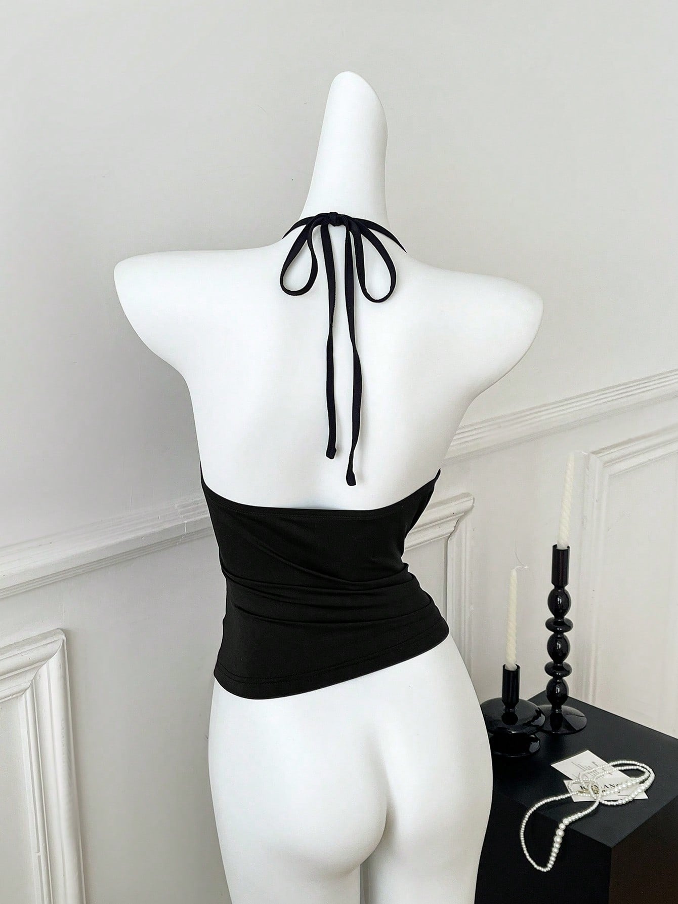 Women's black halter crop tank top with backless design, grommet eyelet detail, slim fit, and medium-stretch knitted fabric.