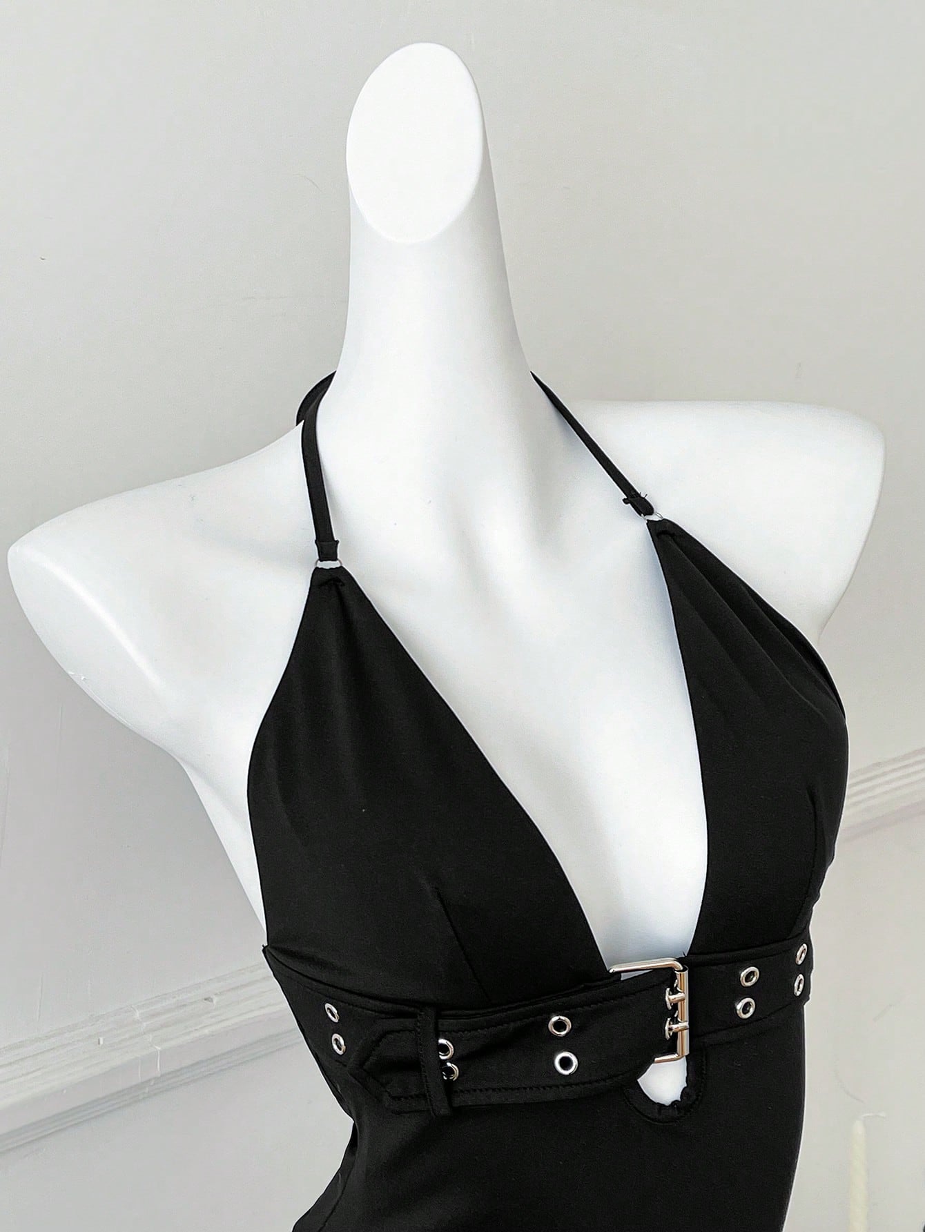 Women's black halter crop tank top with backless design, grommet eyelet detail, slim fit, and medium-stretch knitted fabric.