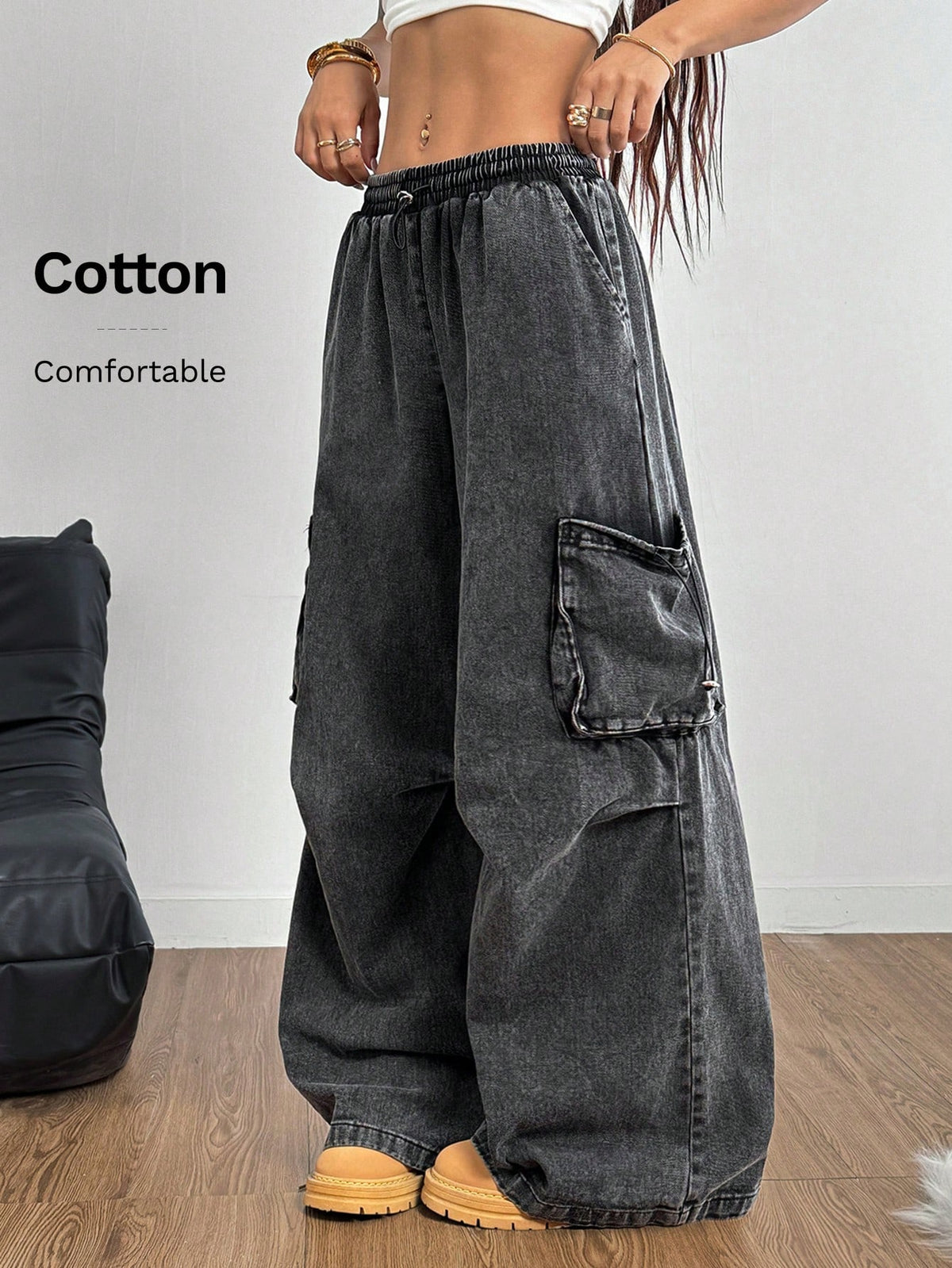 Women's black baggy cargo pants featuring a wide-leg cut, low-rise drawstring waist, and 100% cotton woven fabric.