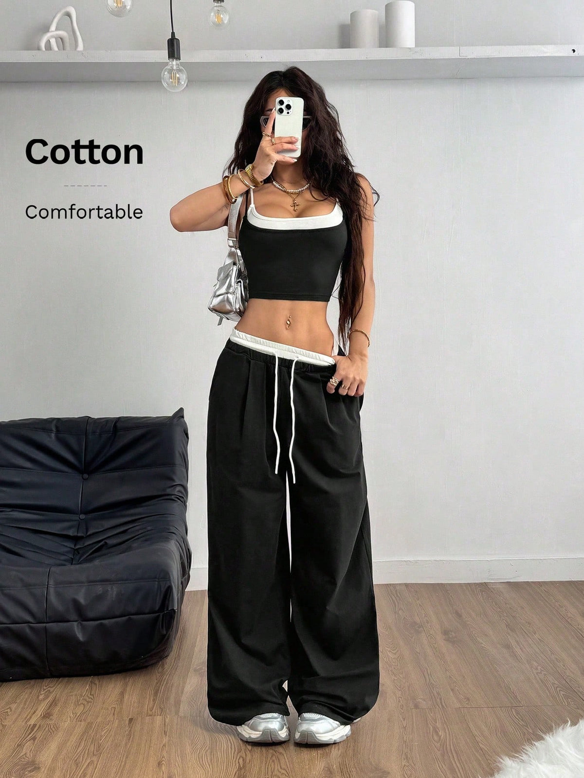 Women's black and white two-piece set featuring a cropped spaghetti strap camisole tank top with contrast binding and matching long drawstring sweatpants with pockets.