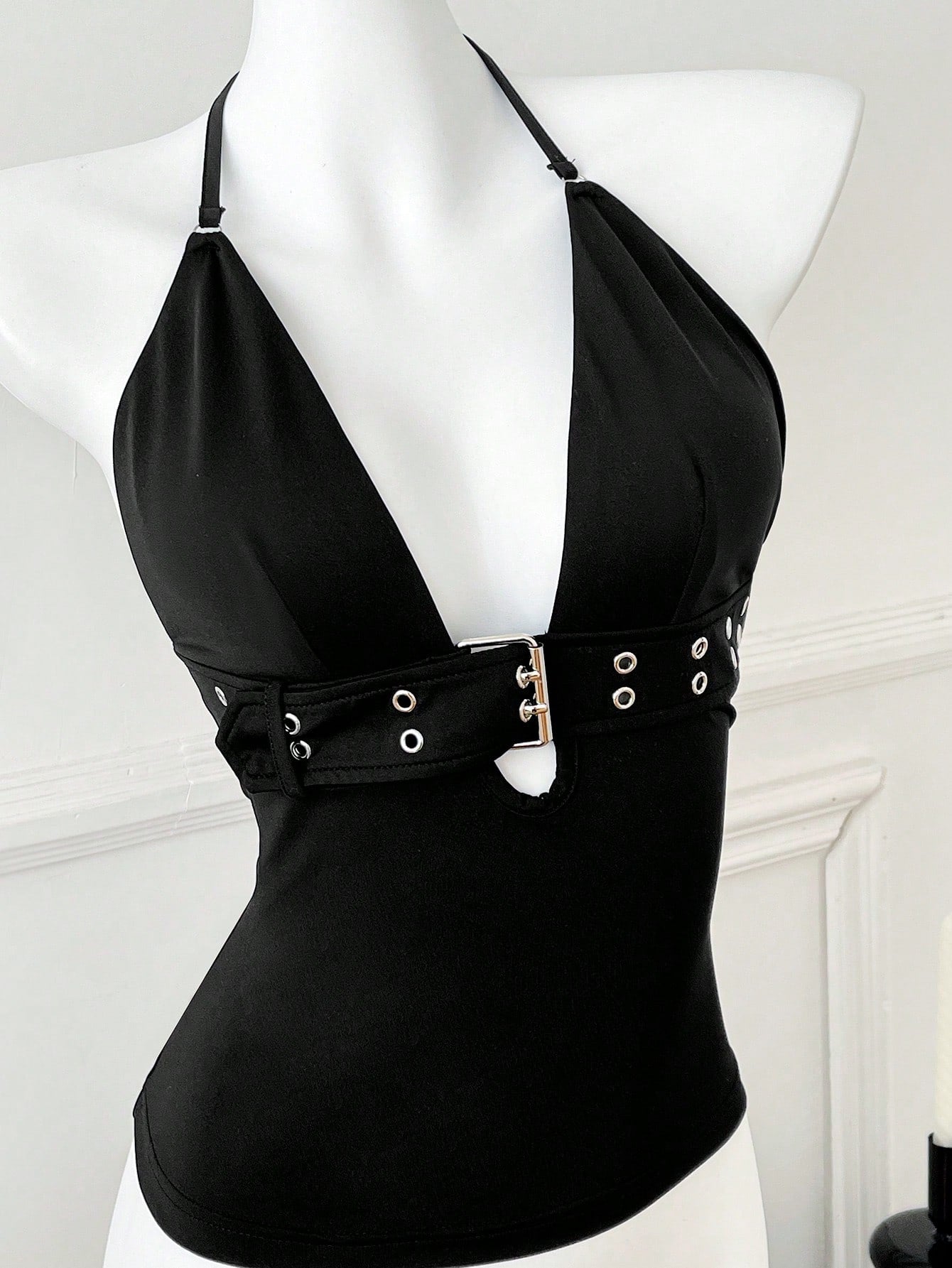 Women's black halter crop tank top with backless design, grommet eyelet detail, slim fit, and medium-stretch knitted fabric.
