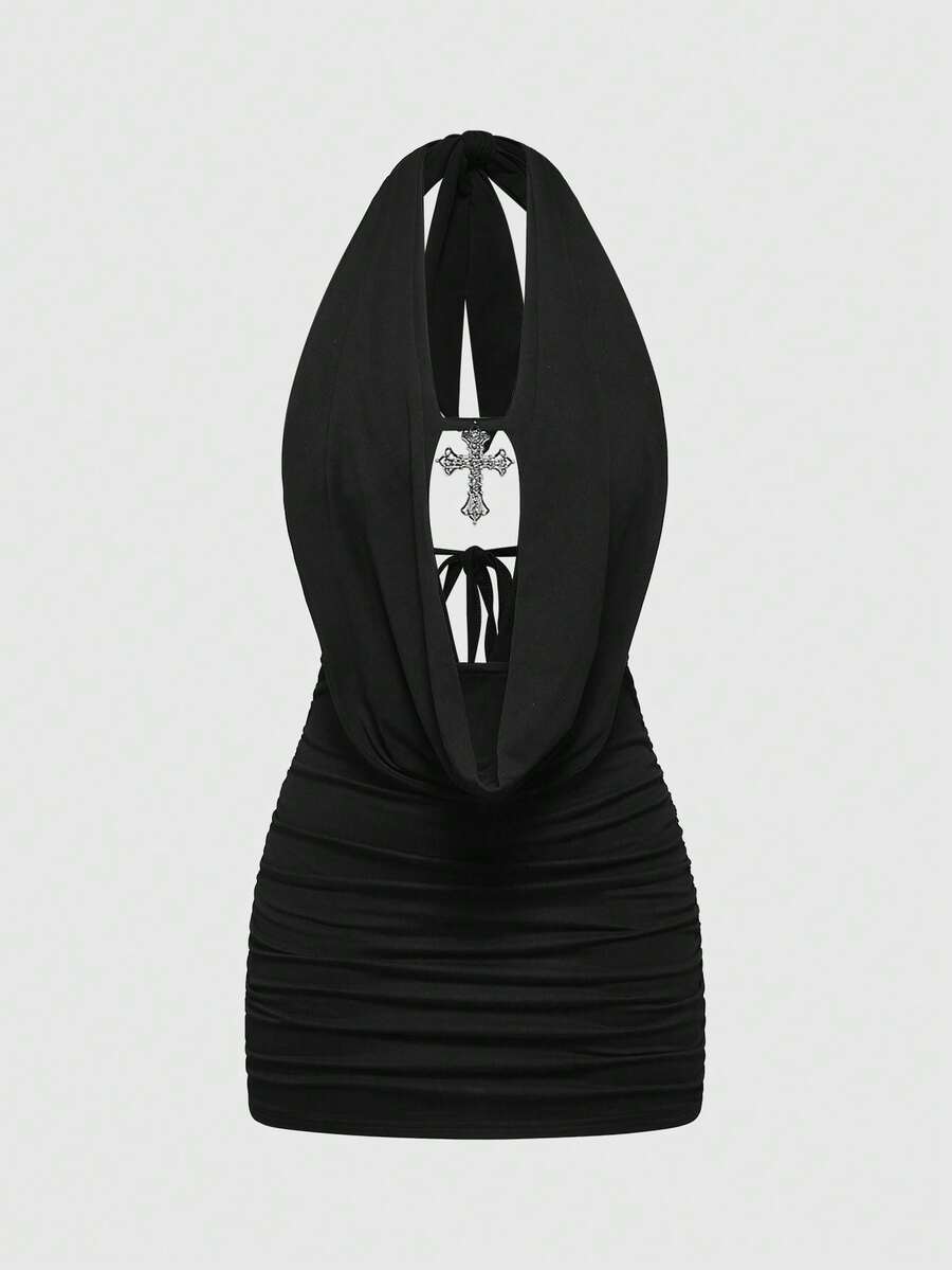 Black backless halter mini dress with ruched details, cut-out back, tied back design, and rhinestone cross pendant accent.