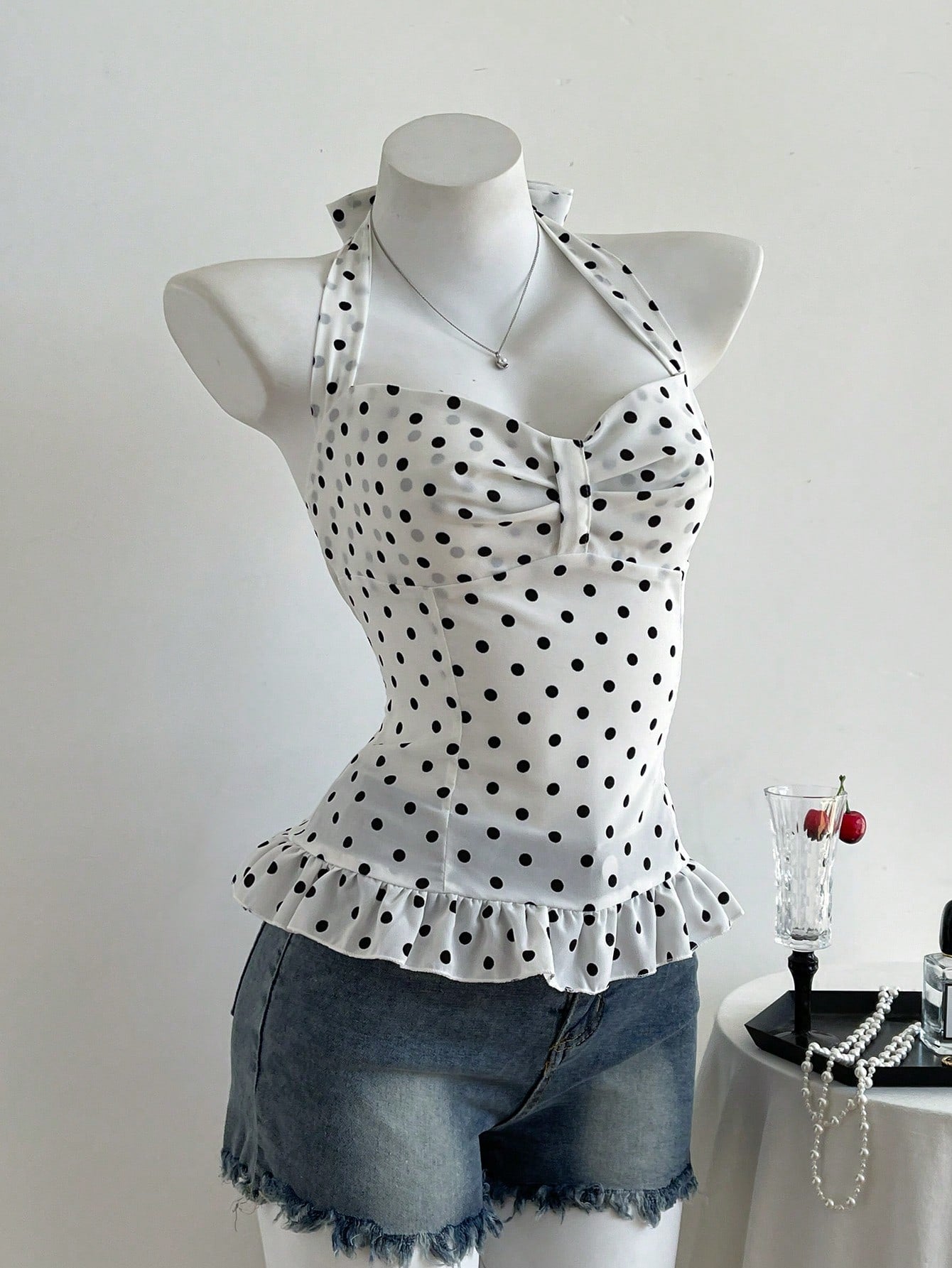 Women's polka dot halter camisole with bow bust detail, ruched and shirred design, slim crop fit, and flared ruffle hem.