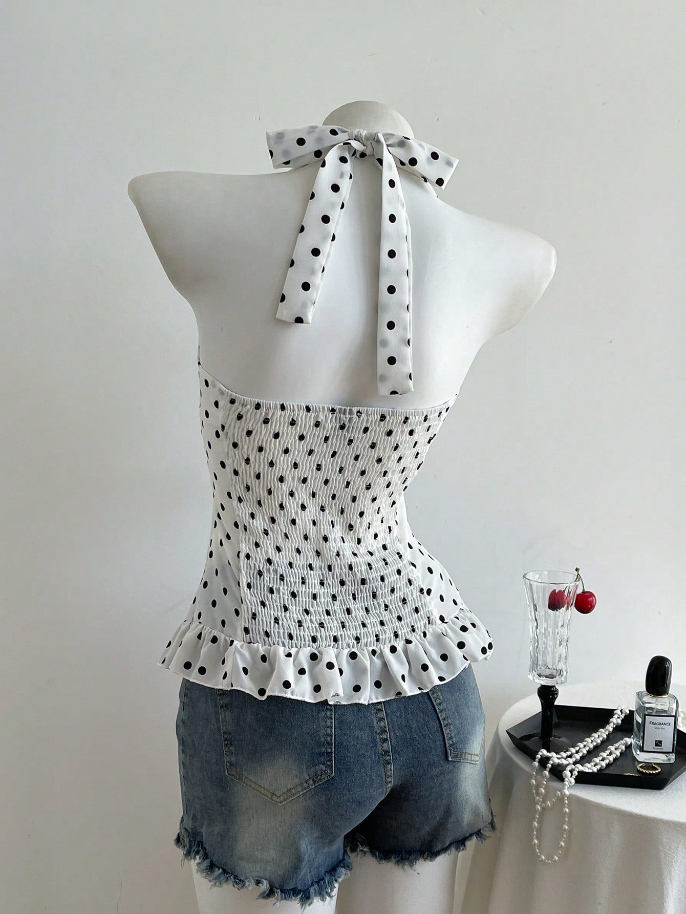 Women's polka dot halter camisole with bow bust detail, ruched and shirred design, slim crop fit, and flared ruffle hem.