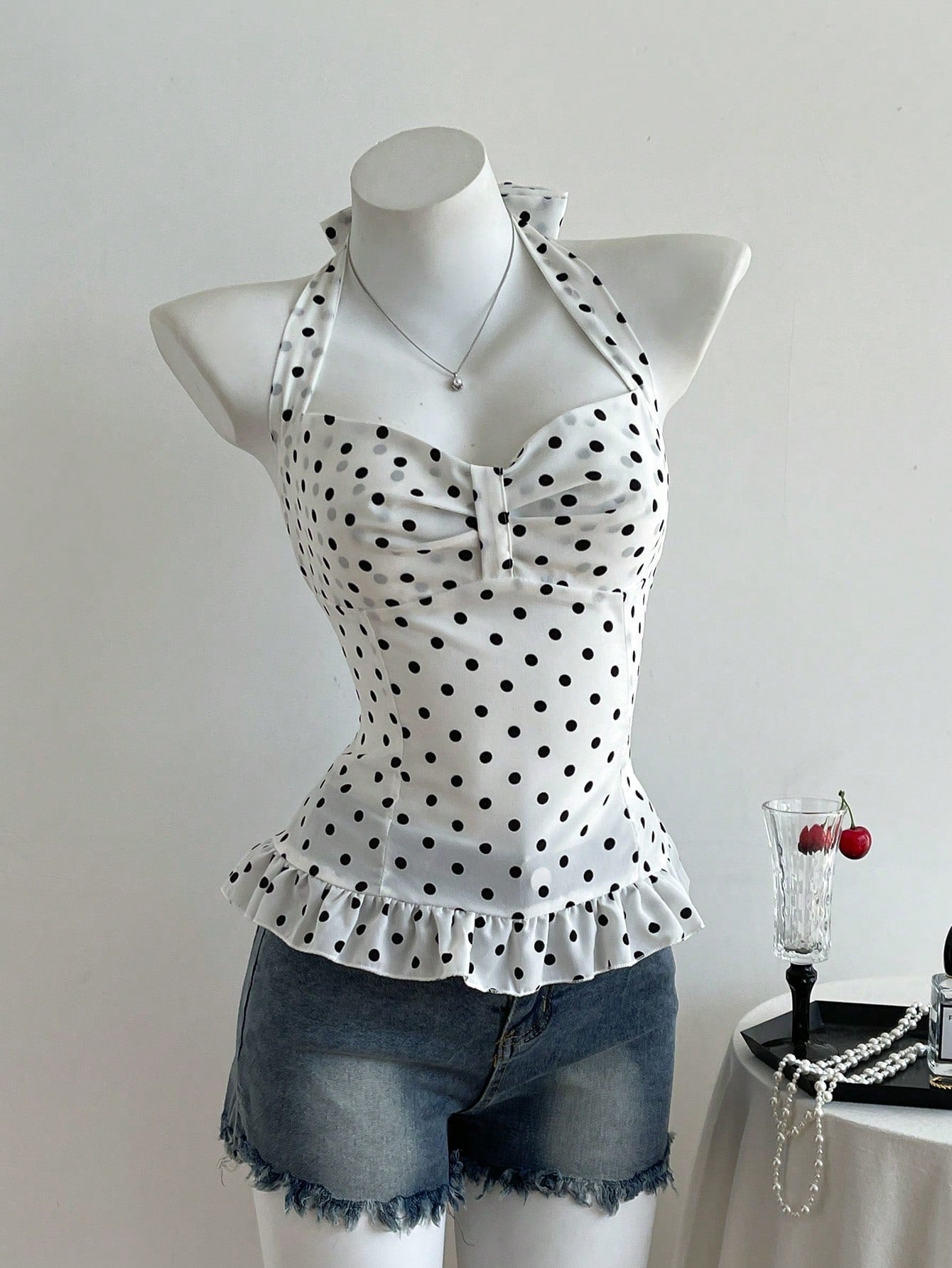 Women's polka dot halter camisole with bow bust detail, ruched and shirred design, slim crop fit, and flared ruffle hem.