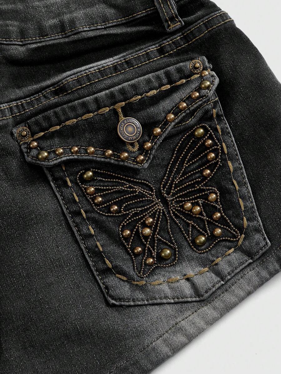Women's Y2K low waist distressed shorts featuring butterfly studded details, pockets, and a zipper fly closure.