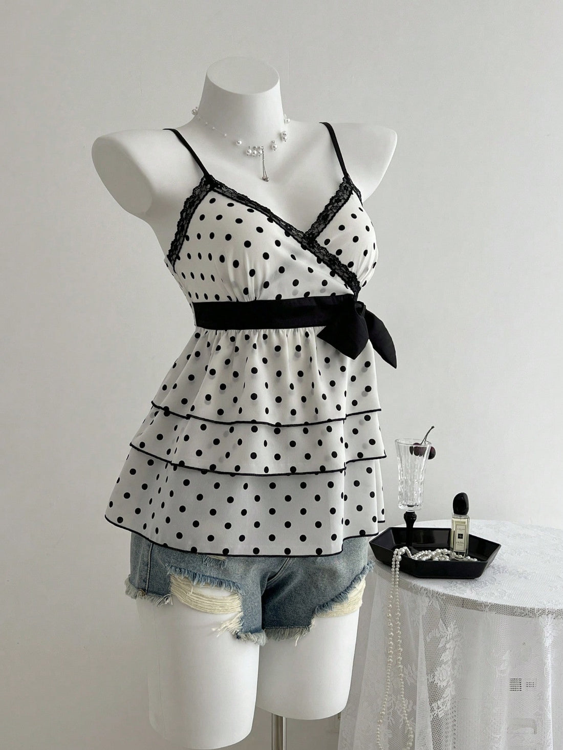 Women's polka dot camisole top with contrast lace trim, tank vest neckline, slim fit, and flared ruffle hem.