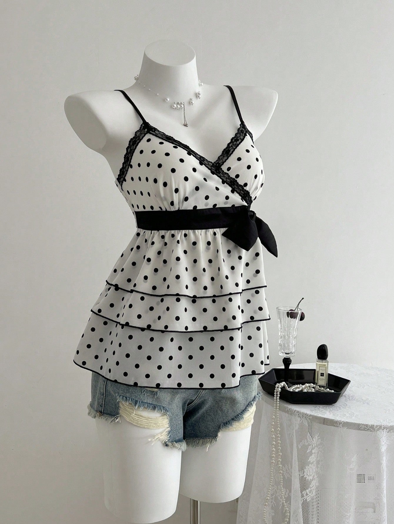 Women's polka dot camisole top with contrast lace trim, tank vest neckline, slim fit, and flared ruffle hem.