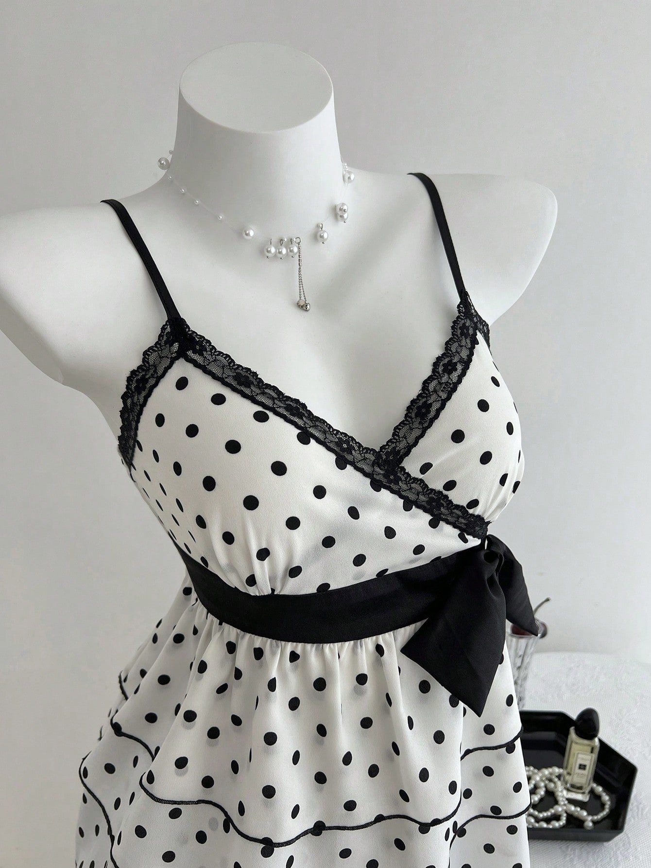 Women's polka dot camisole top with contrast lace trim, tank vest neckline, slim fit, and flared ruffle hem.