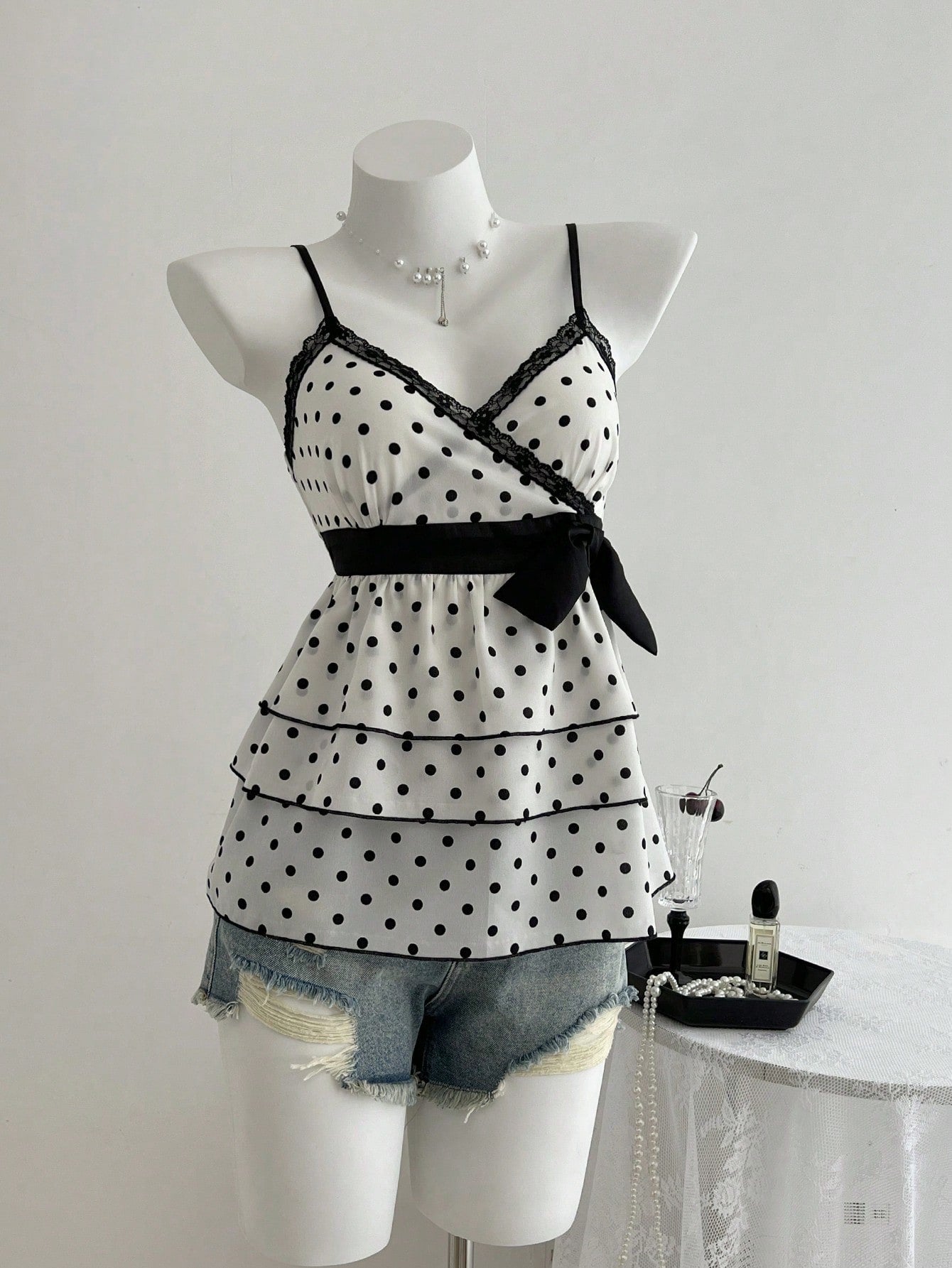 Women's polka dot camisole top with contrast lace trim, tank vest neckline, slim fit, and flared ruffle hem.