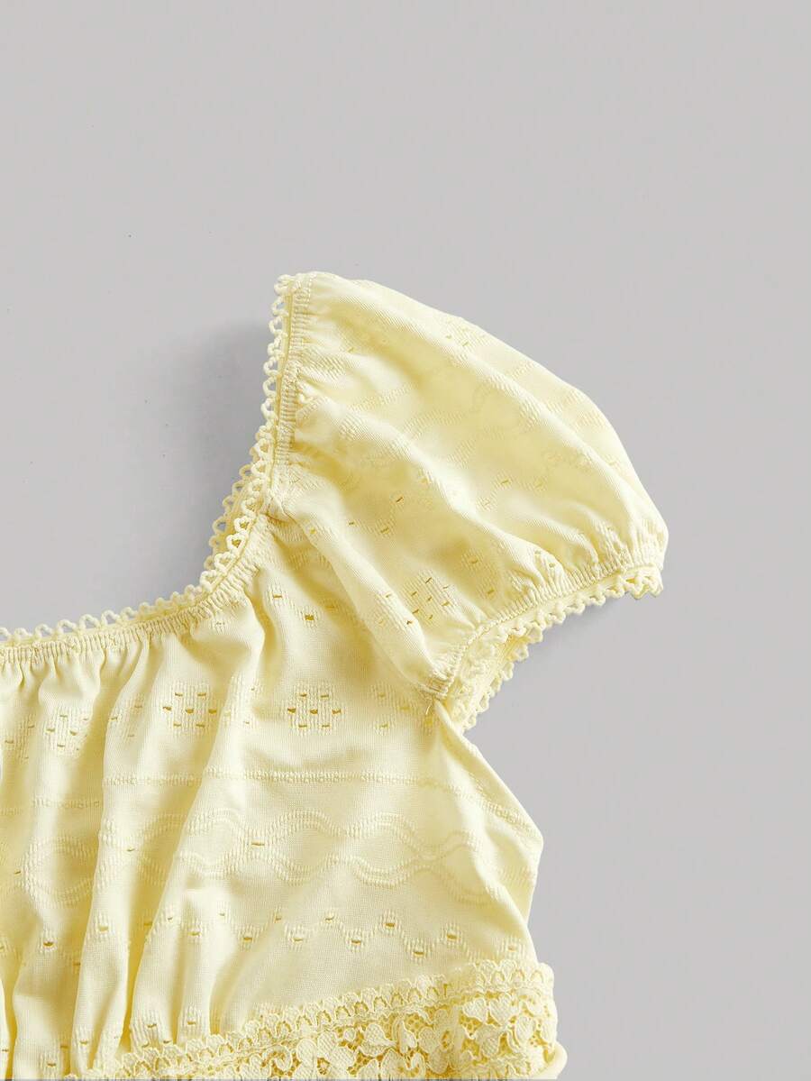 Yellow short puff sleeve tee featuring a square neckline, ruched bust with knot detail, eyelet embroidery, and a gathered waist.